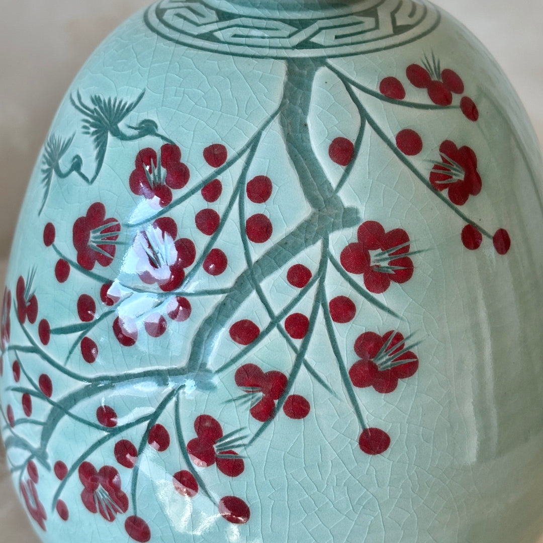 Decorative ceramic vase with red floral design on a light blue background