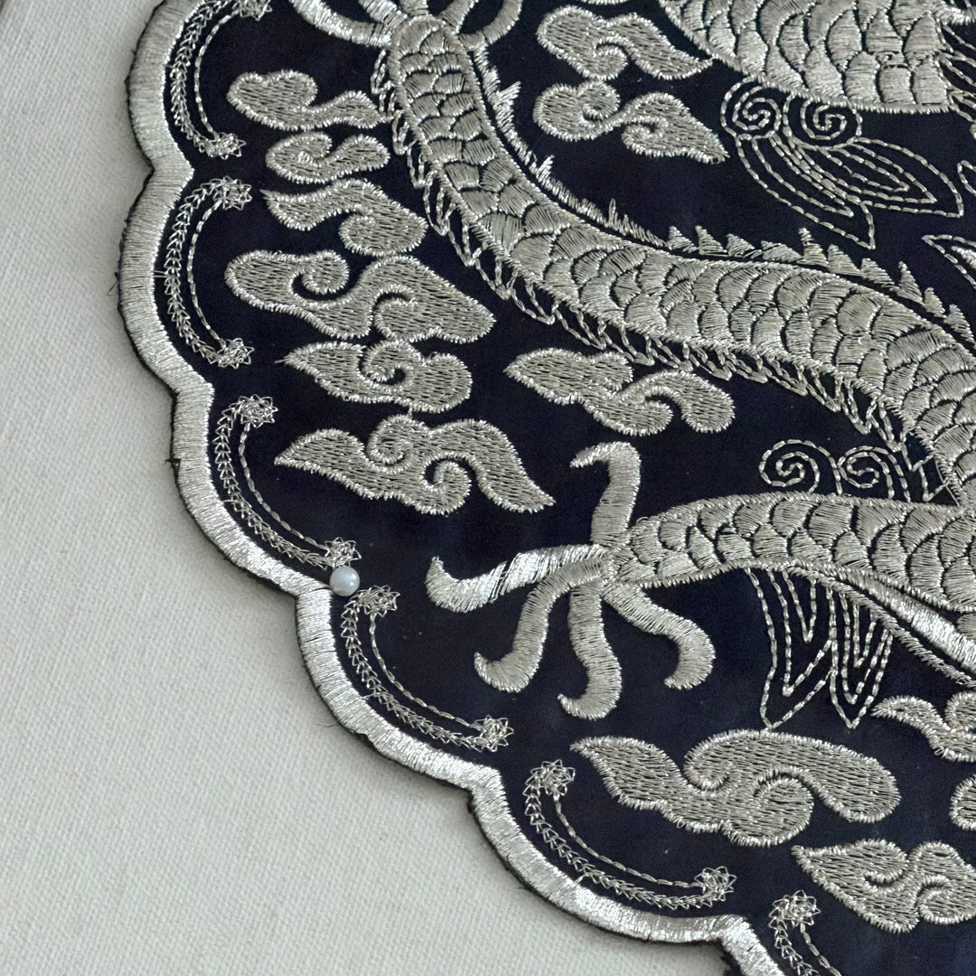 Close-up of intricate silver embroidery on a dark fabric background