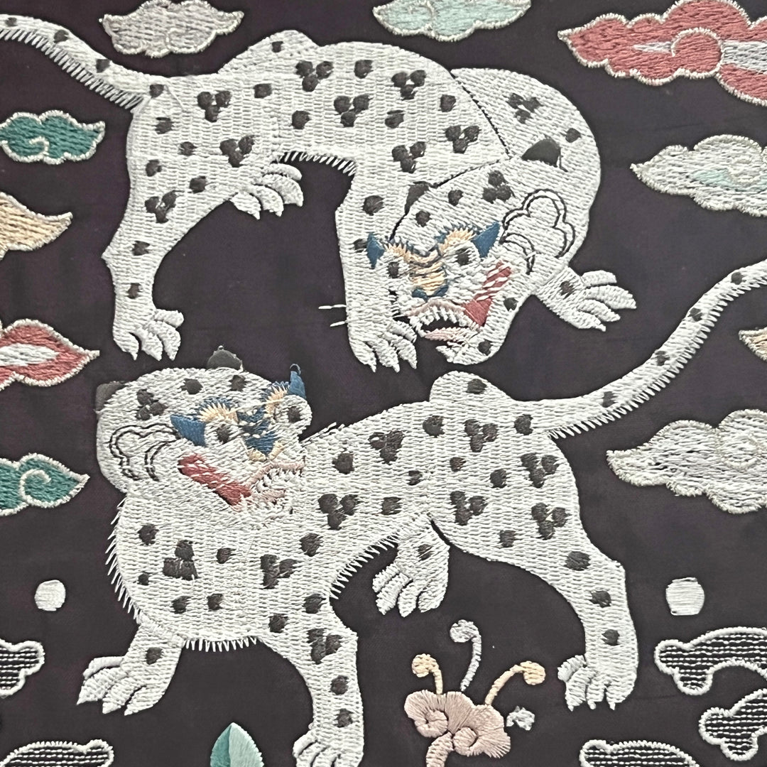 Embroidered design of tigers on a dark background