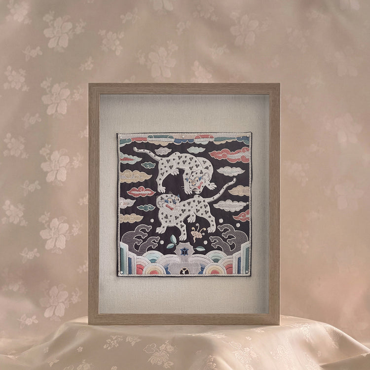 Framed artwork with a design of leopards on a floral wall background