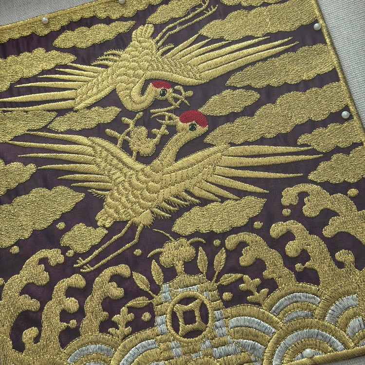 Embroidered fabric with a gold phoenix design on a dark background