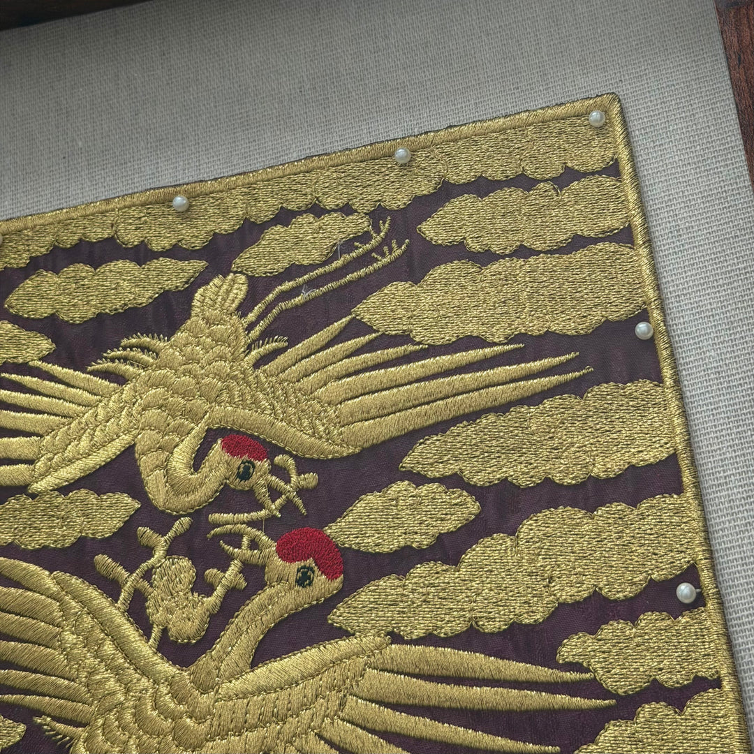 Embroidered design of two cranes on a fabric background