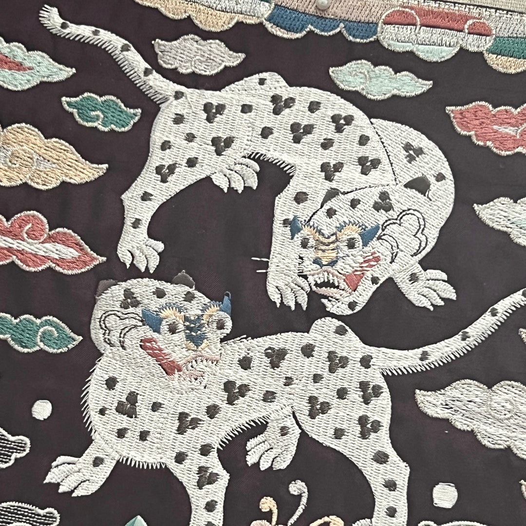 Embroidered design of tigers on a dark fabric background
