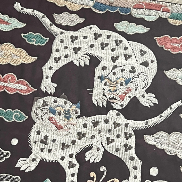 Embroidered design of tigers on a dark fabric background