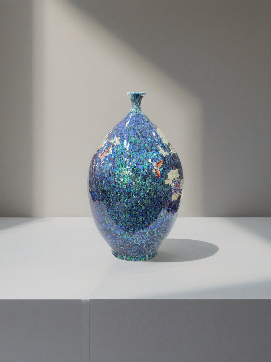 Decorative vase with a multicolored speckled design on a white surface with a gray background