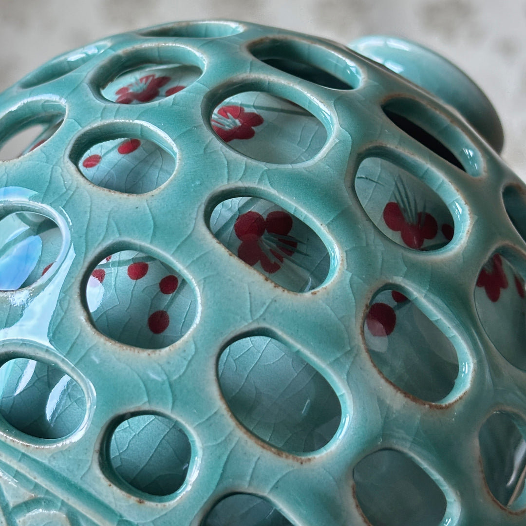 Close-up of a ceramic incense burner with floral designs on a textured surface.