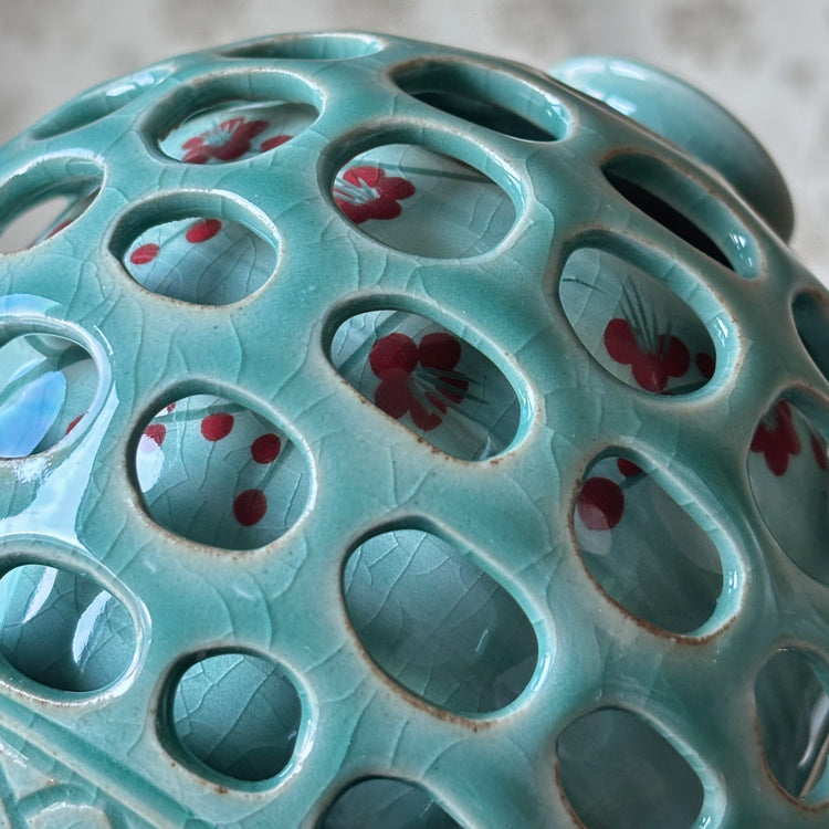 Close-up of a ceramic incense burner with floral designs on a textured surface.
