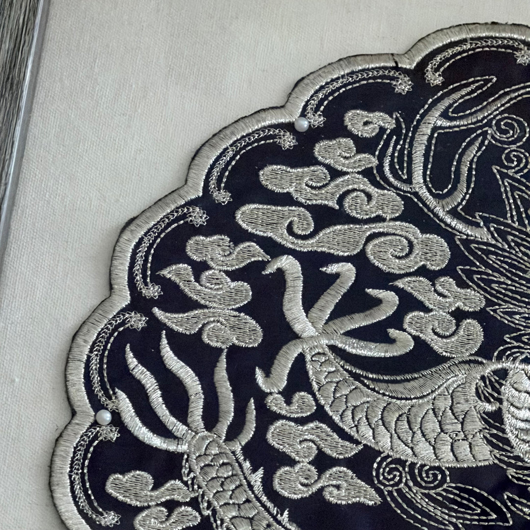 Close-up of intricate silver embroidery on a dark fabric background