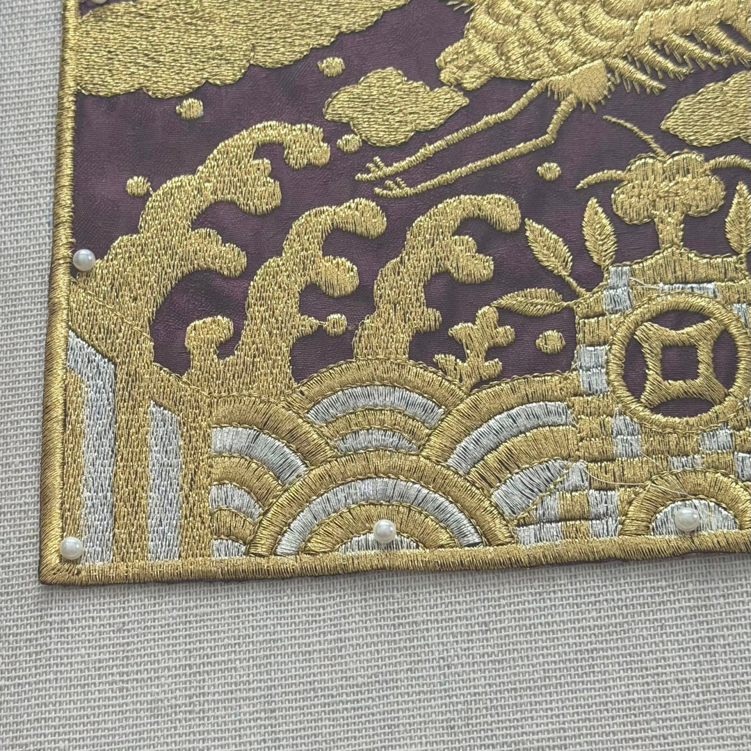 Close-up of embroidered fabric with intricate patterns on a wooden frame.