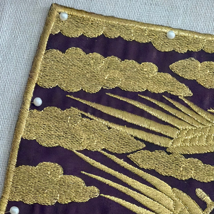 Embroidered gold clouds on a purple fabric background
