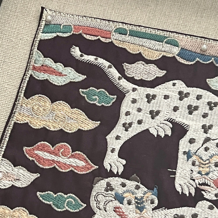 Embroidered fabric with a white tiger design on a dark background